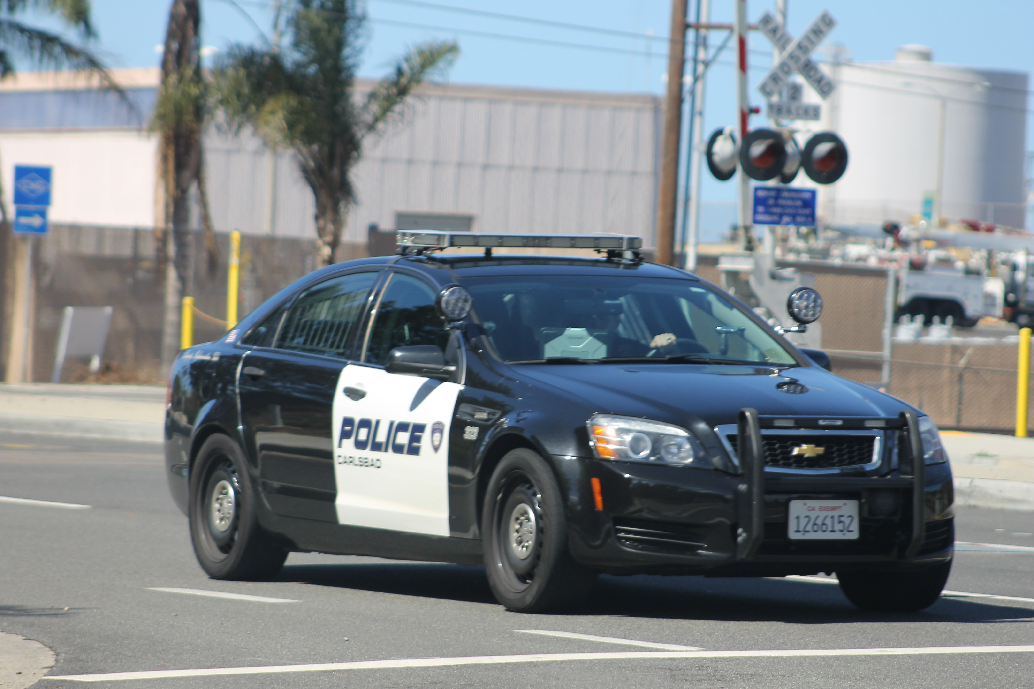 Black-and-white Carlsbad Police patrol car marked 'POLICE' driving on a road.