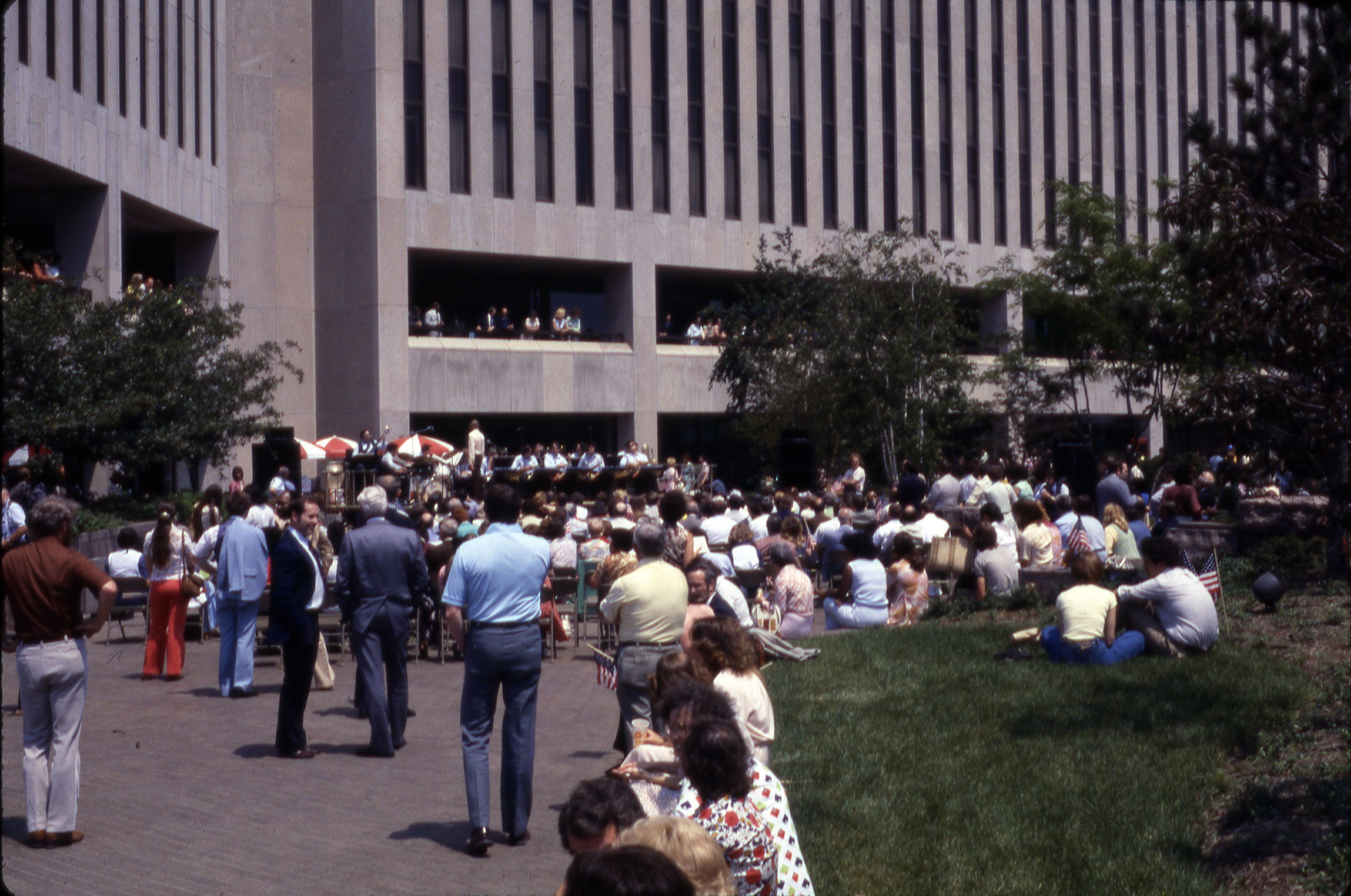 Large crowd gathered in an outdoor urban plaza watching a free outdoor concert.