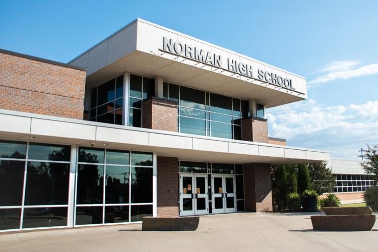 Two-story brick and glass school building with signage reading Norman High School above the entrance.