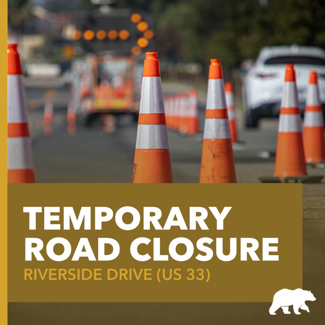 Graphic with bold text reading 'Temporary Road Closure' and 'Riverside Drive US 33' over a background of orange traffic cones.