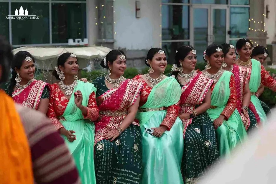 Group of women in matching traditional Indian attire performing a cultural program outdoors.