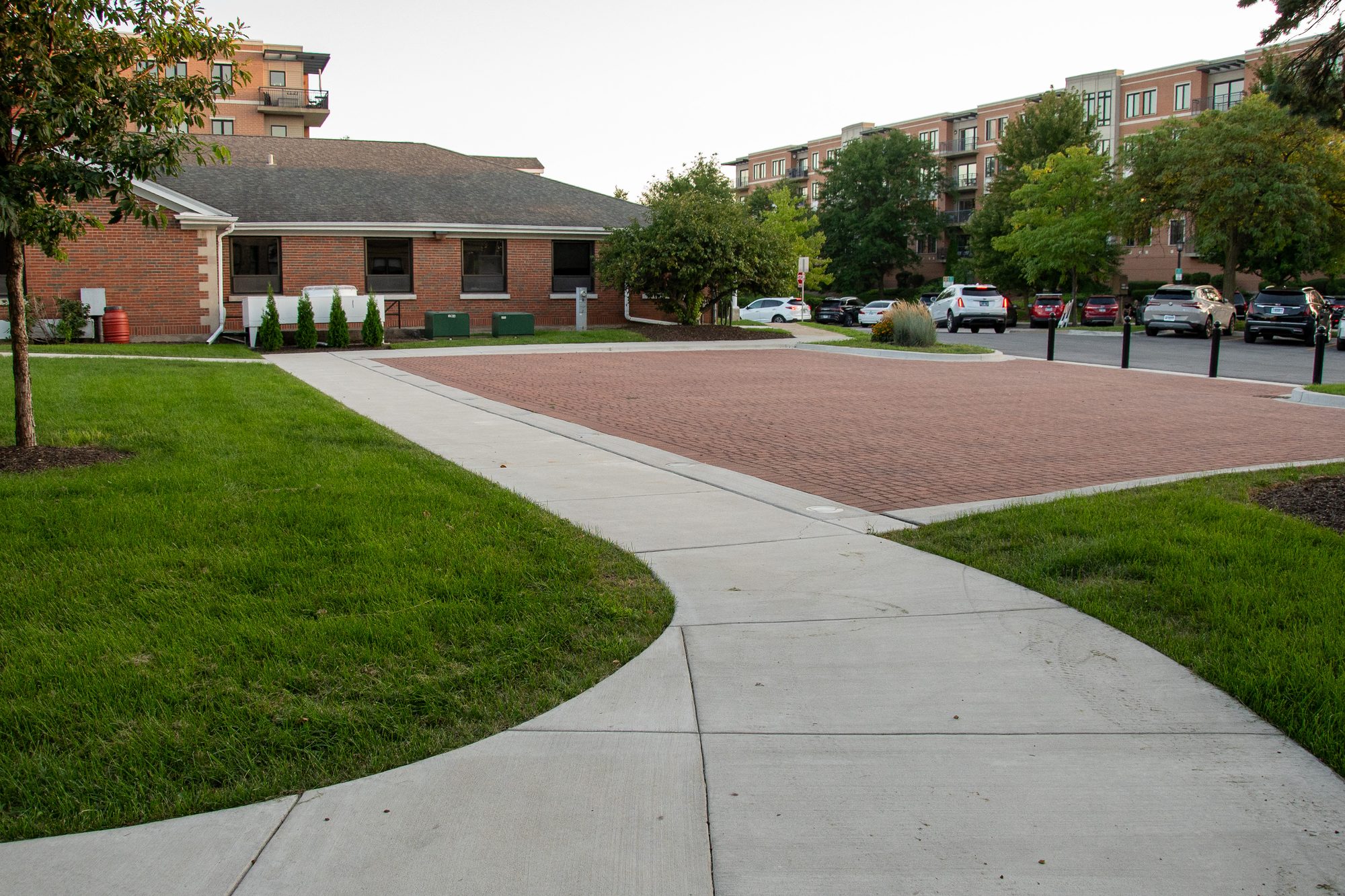 Low brick building beside a landscaped lawn and paved plaza.