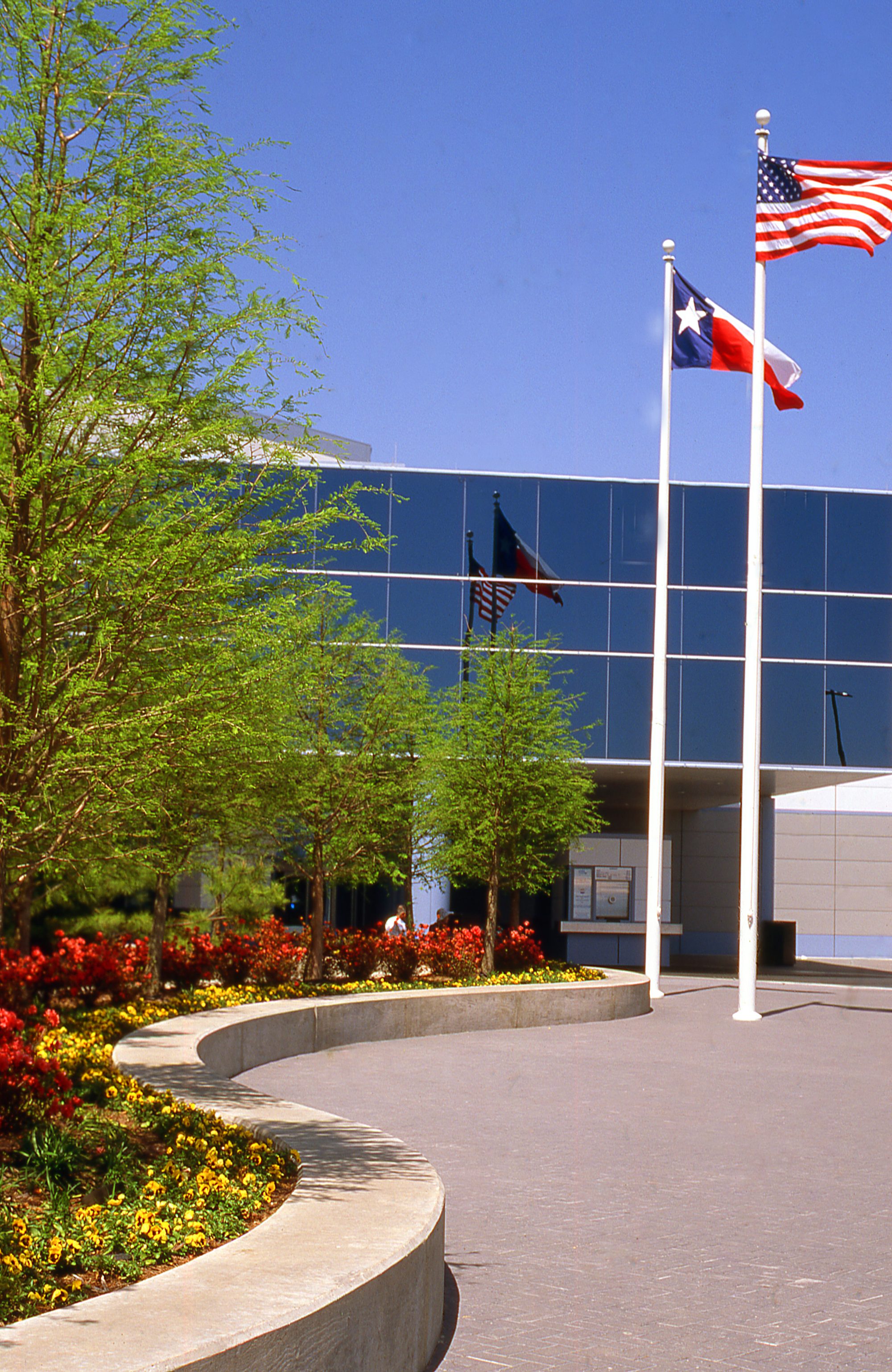 Flagpoles with Texas Lone Star Flag and American Flag at entrance to Johnson Space Center Visitor Center near Houston Texas