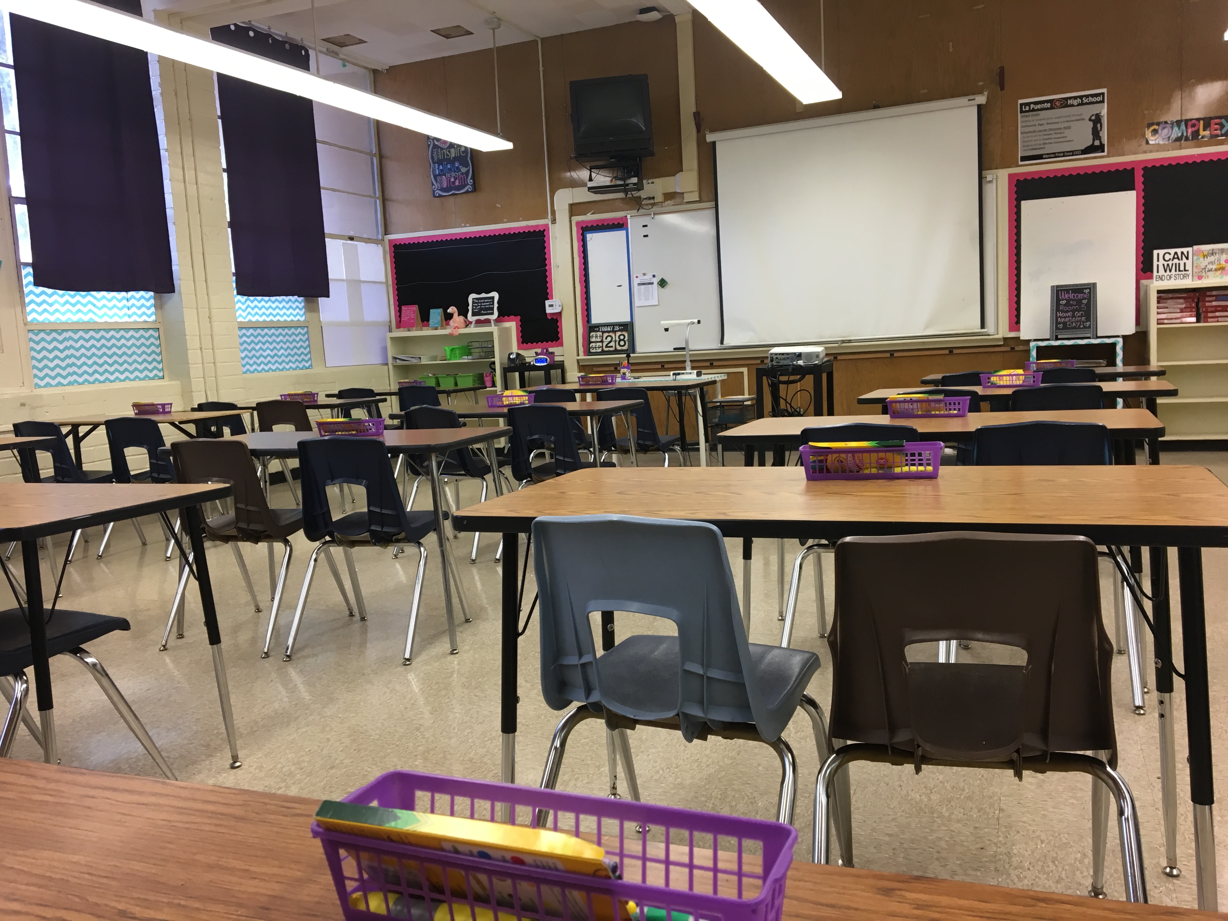 Empty elementary school classroom with rows of desks, a whiteboard, and bulletin boards.