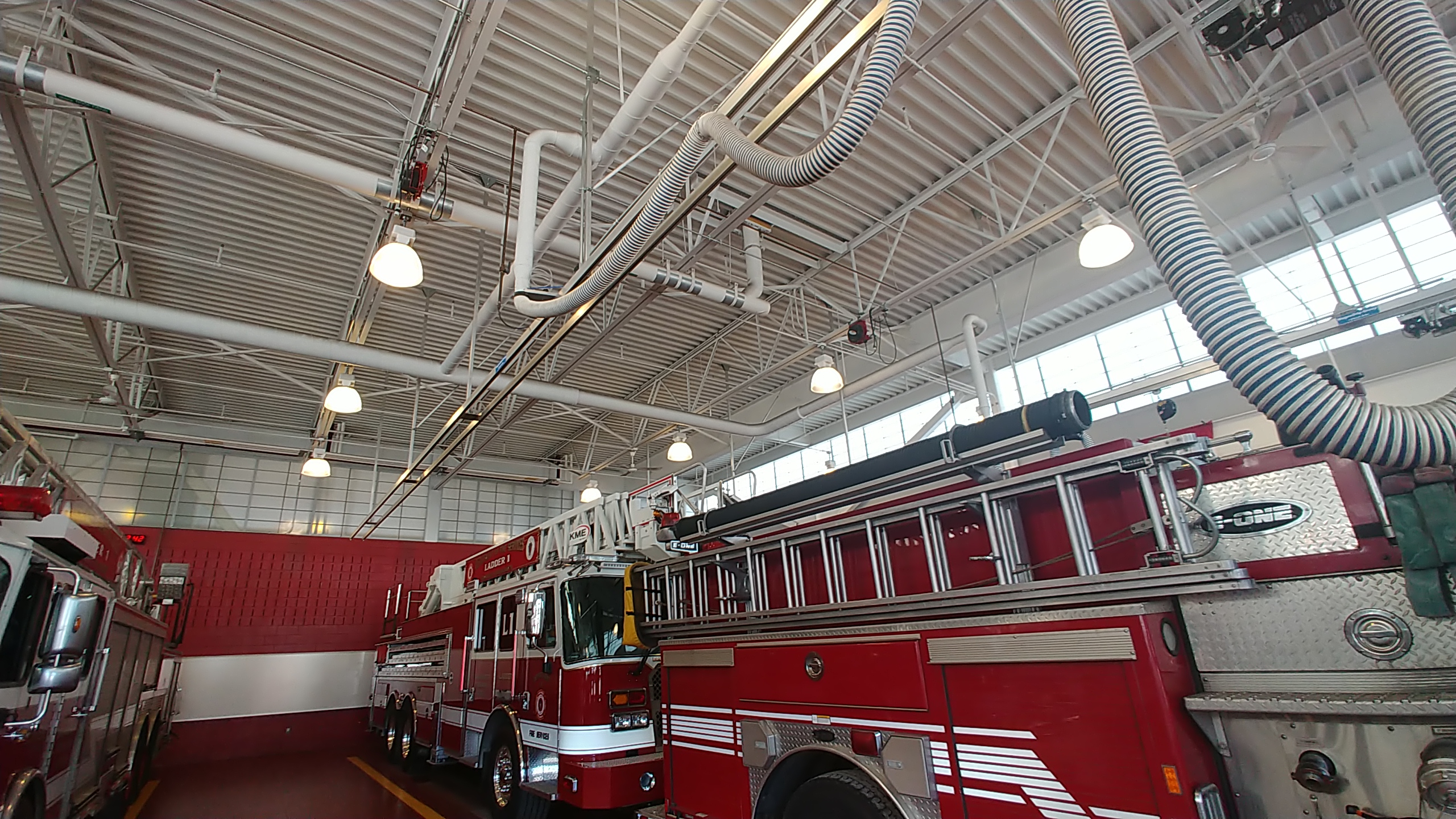 A red ladder fire truck parked inside a modern fire station apparatus bay.