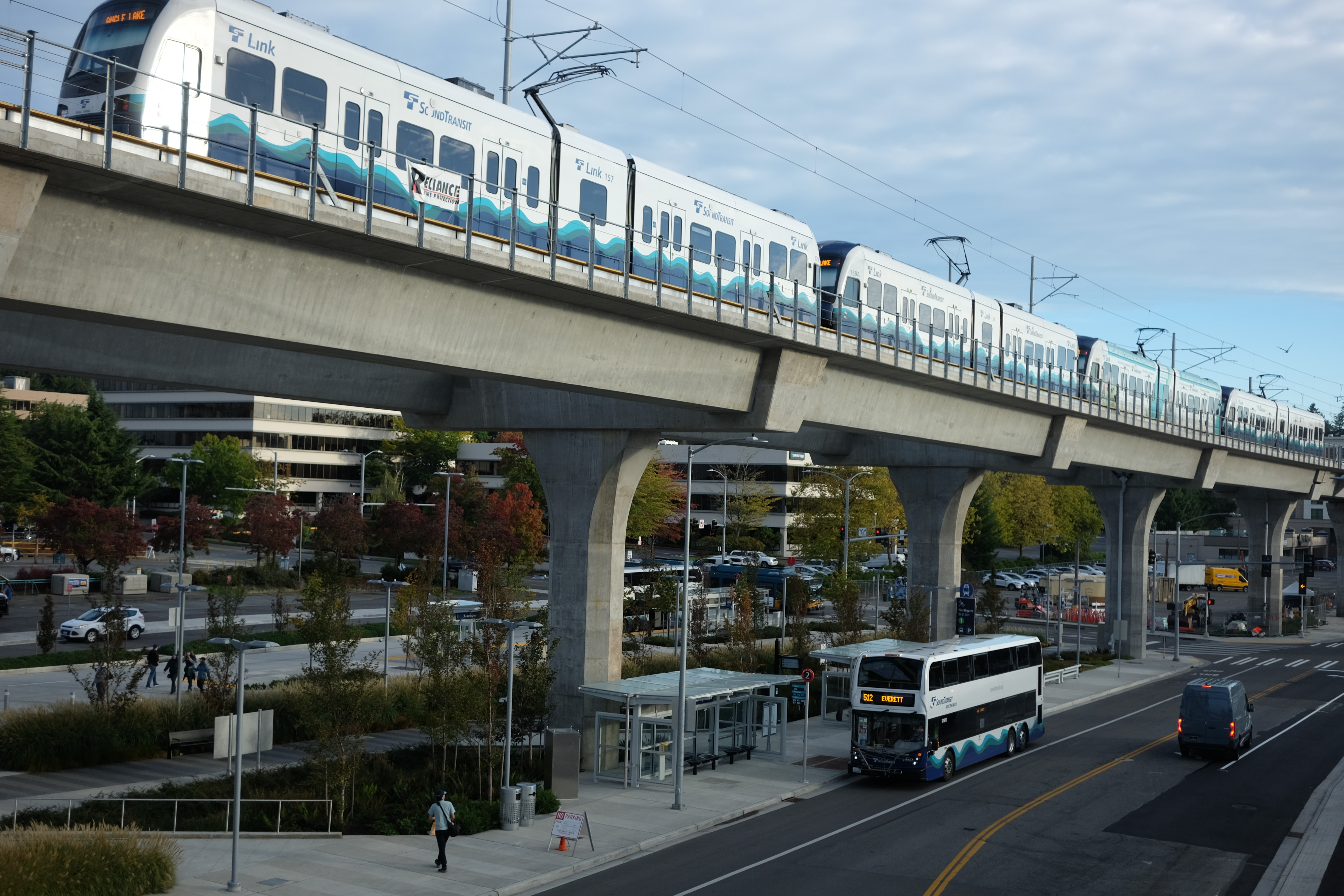 A light rail train on an elevated concrete guideway above a street below.