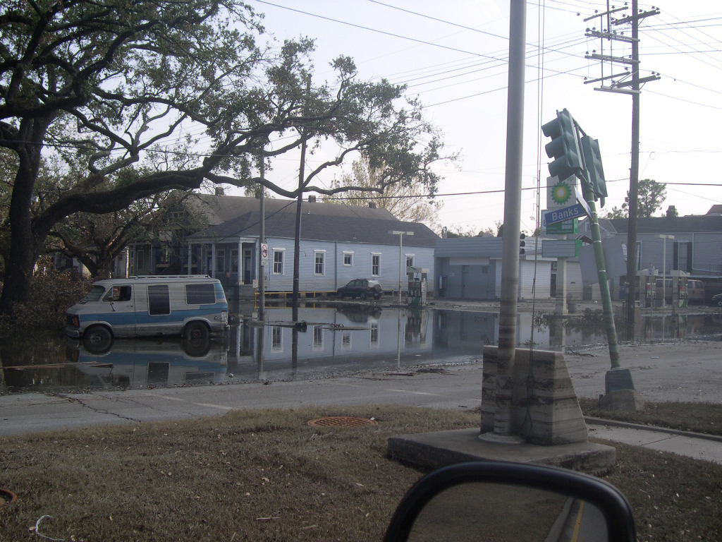 Flooded residential street with standing water and a partially submerged van.