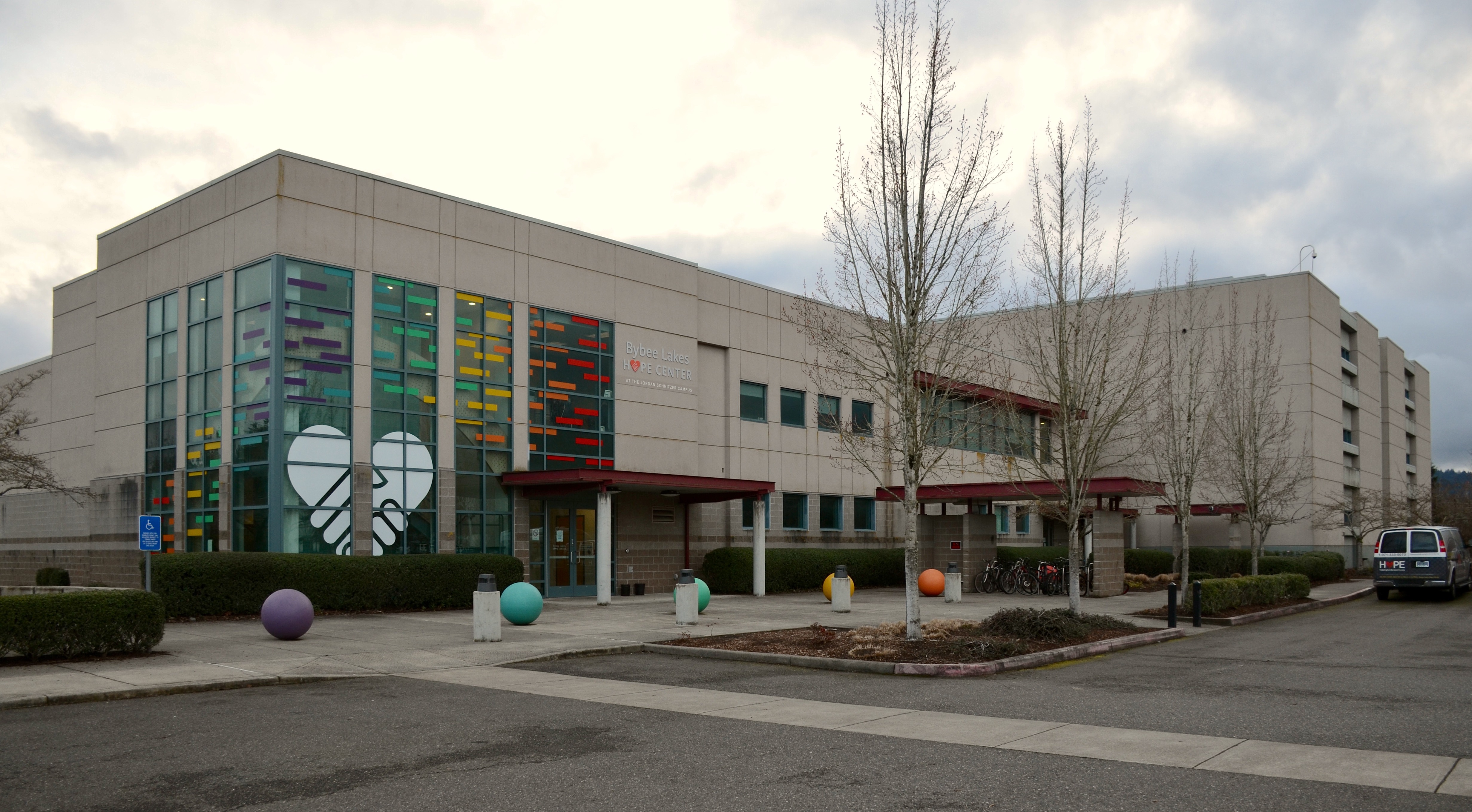 Large institutional building with colorful facade panels and decorative spheres outside a homeless shelter.