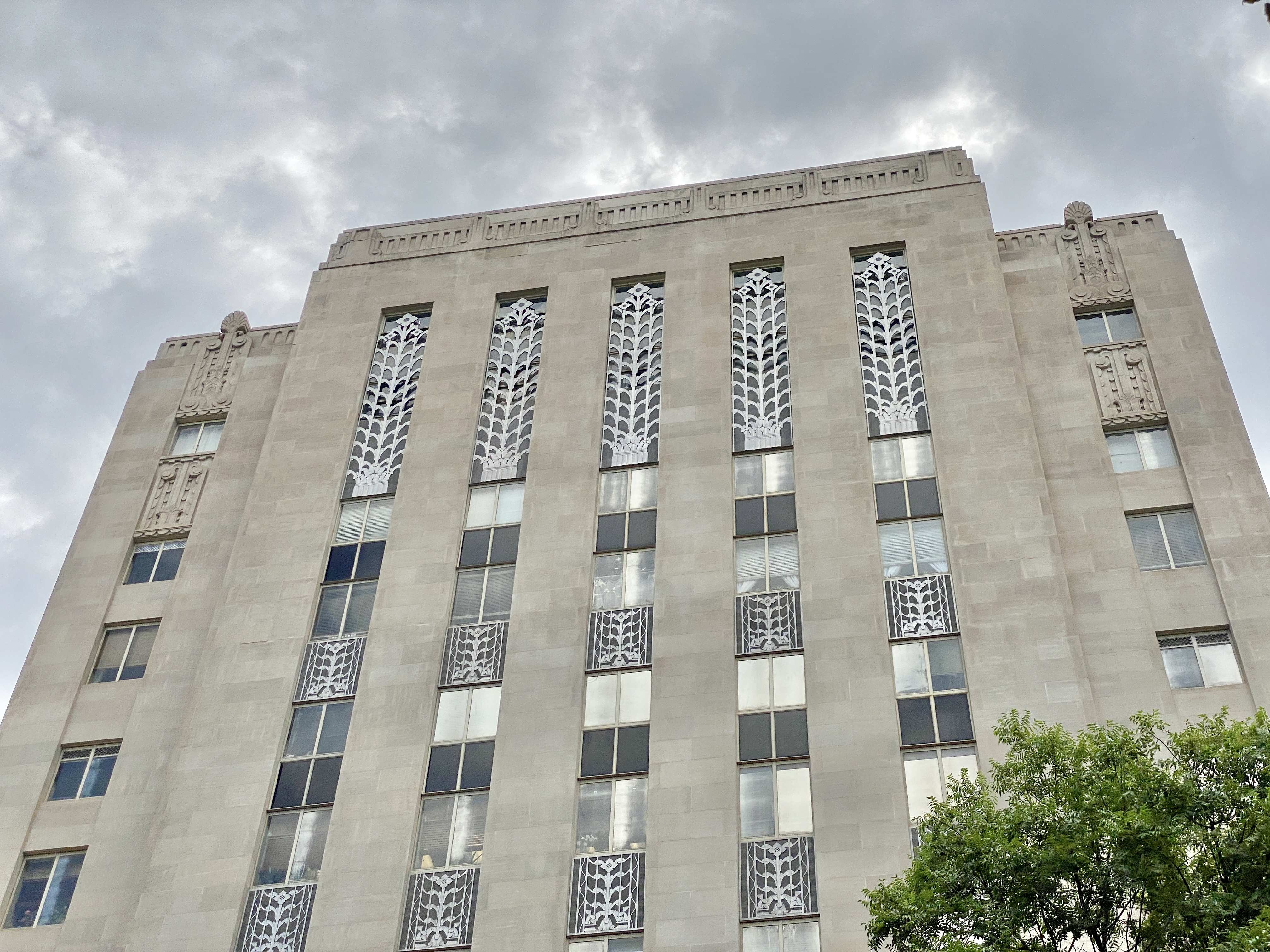 Low-angle view of an Art Deco stone government building with ornate vertical panels.