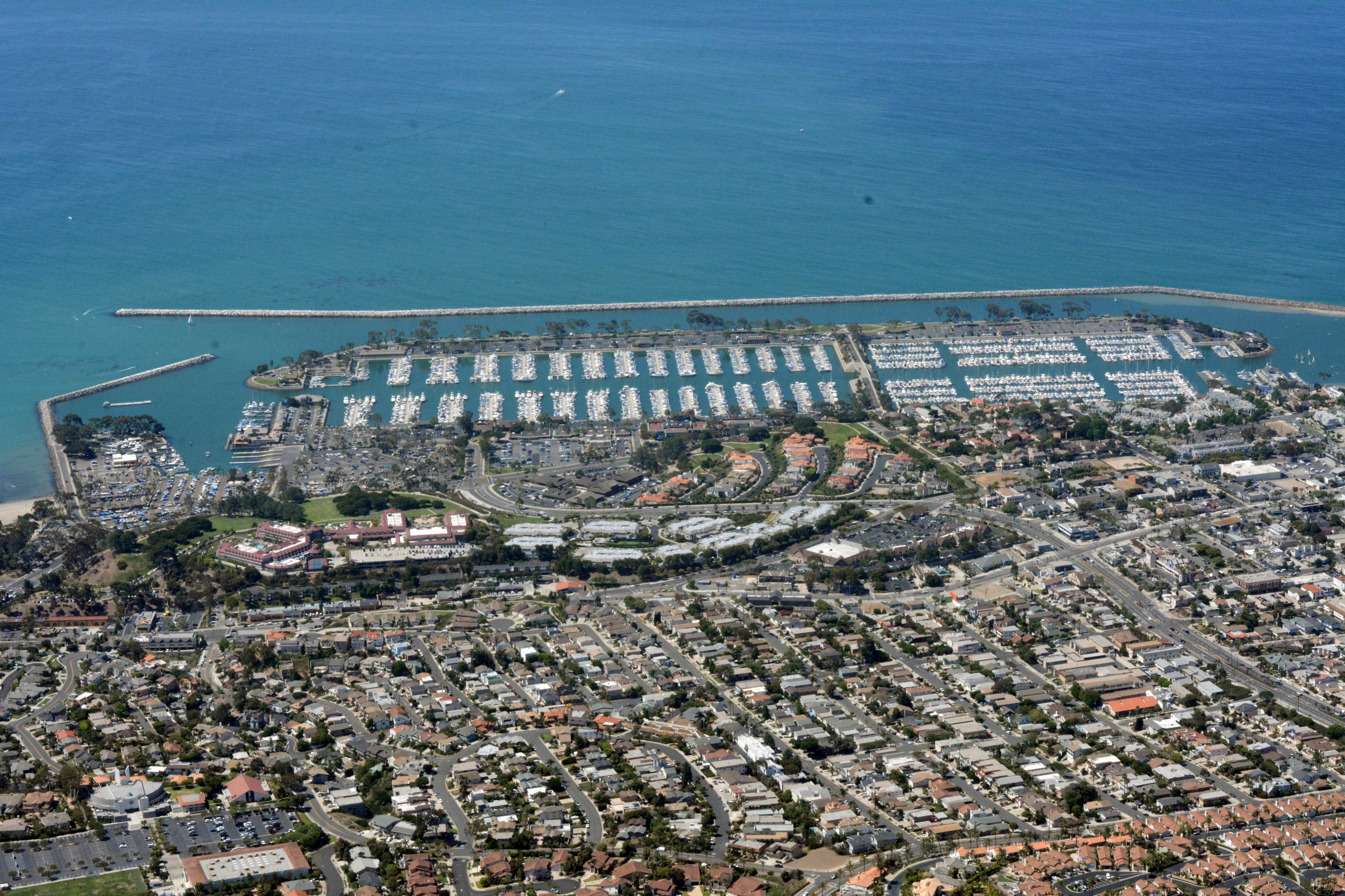 Aerial view of Dana Point Harbor marina with hundreds of boat slips and a breakwater.