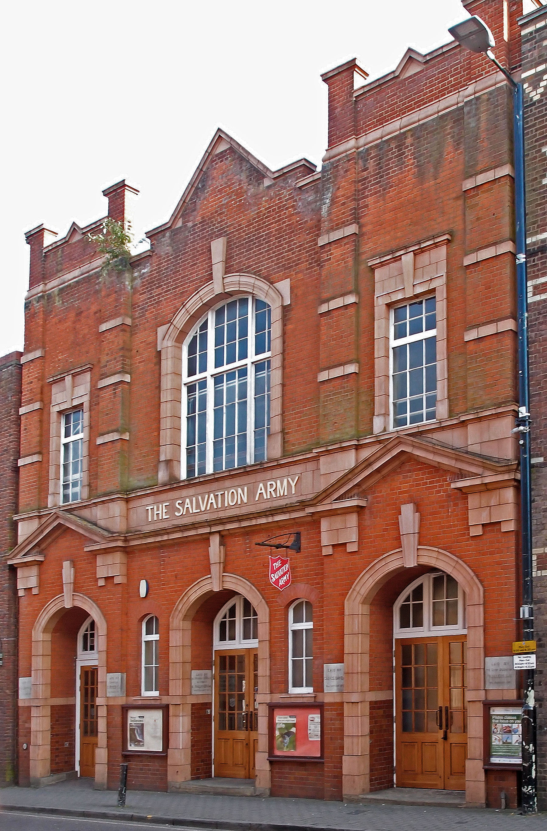 Red-brick Salvation Army building with shield logo above arched entrance doors.