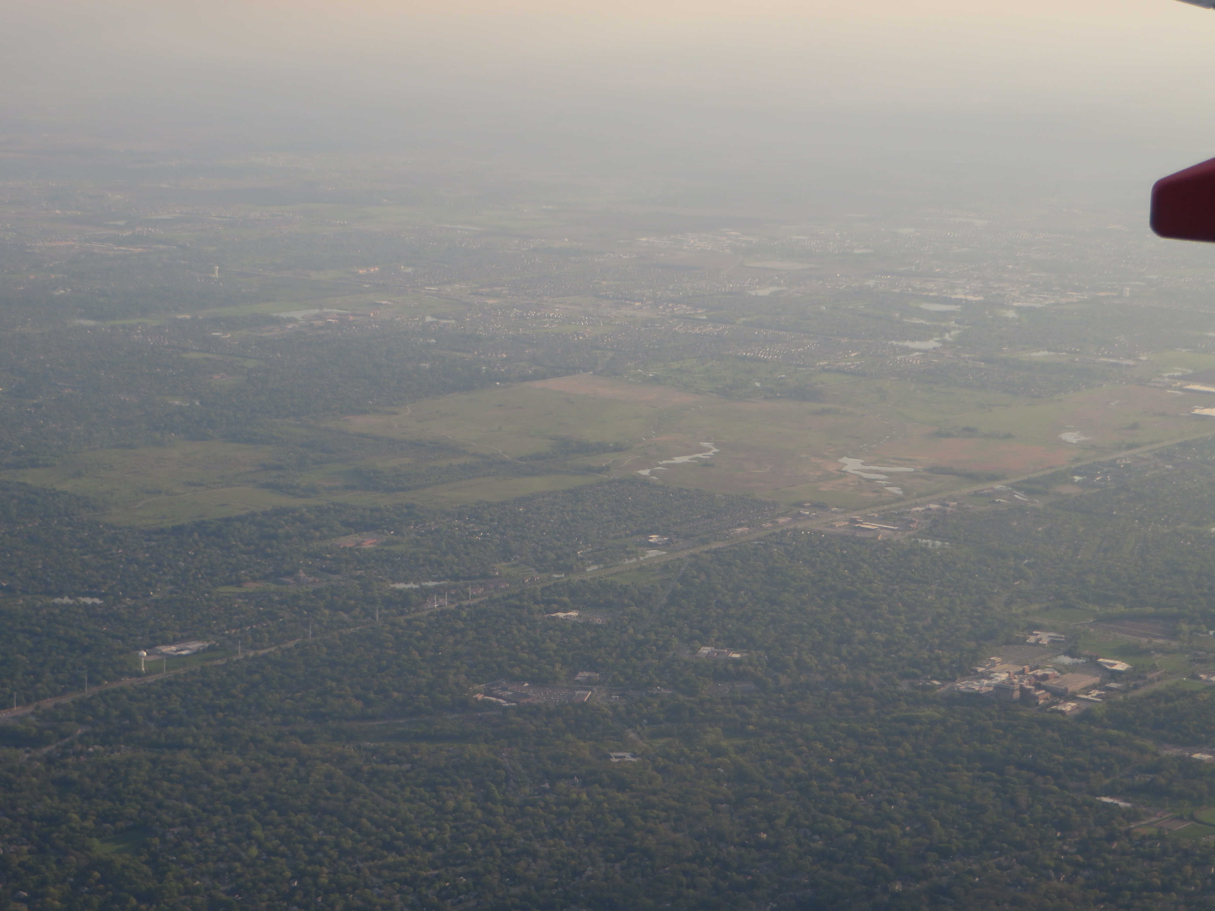 Aerial view of expansive green forest preserve land and open fields amid suburban development