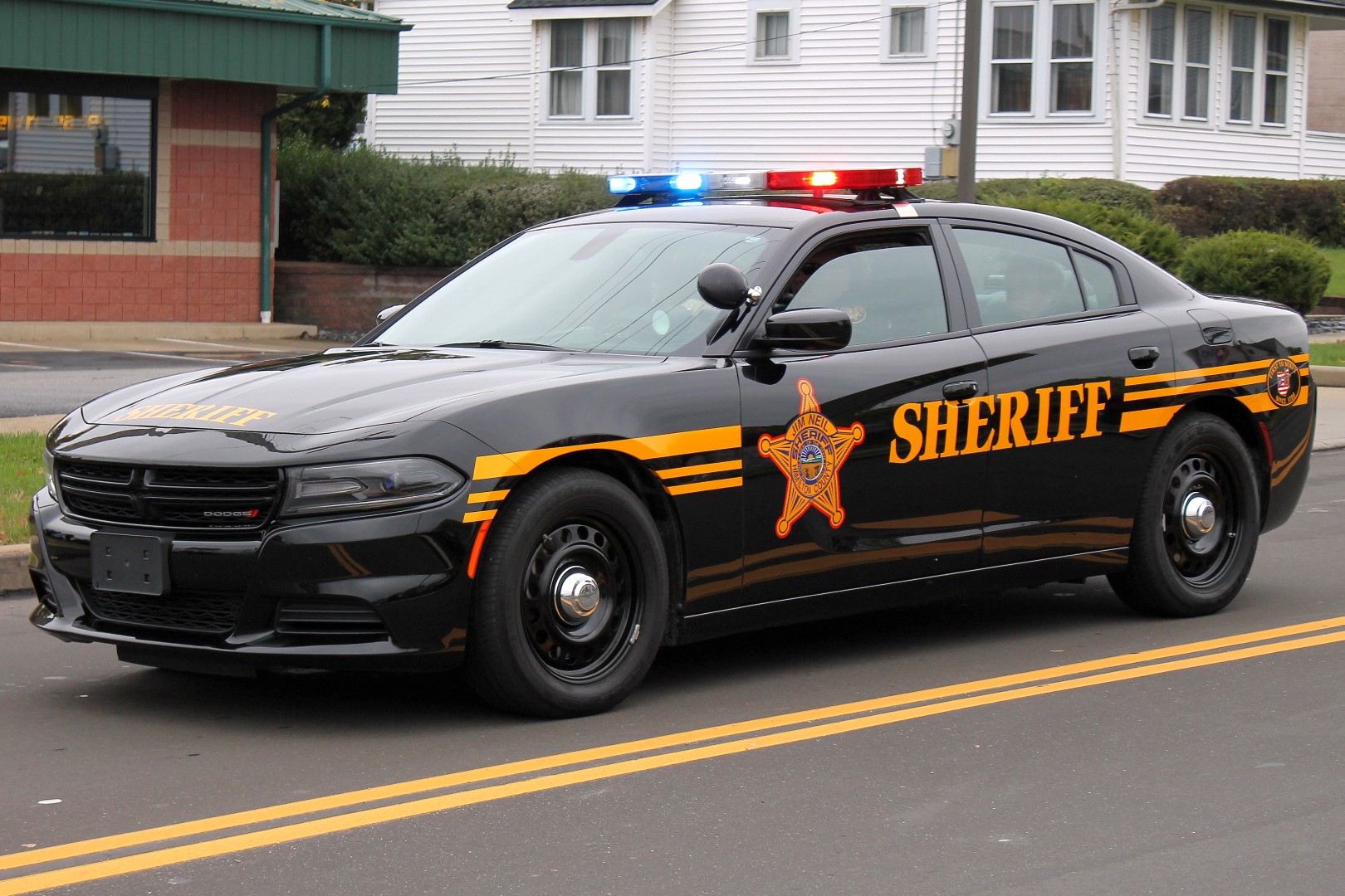 Black Hamilton County Sheriff patrol car with gold lettering and active roof light bar.