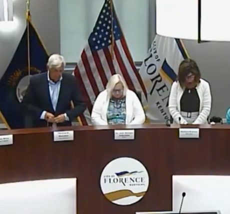 city council members pray before a meeting
