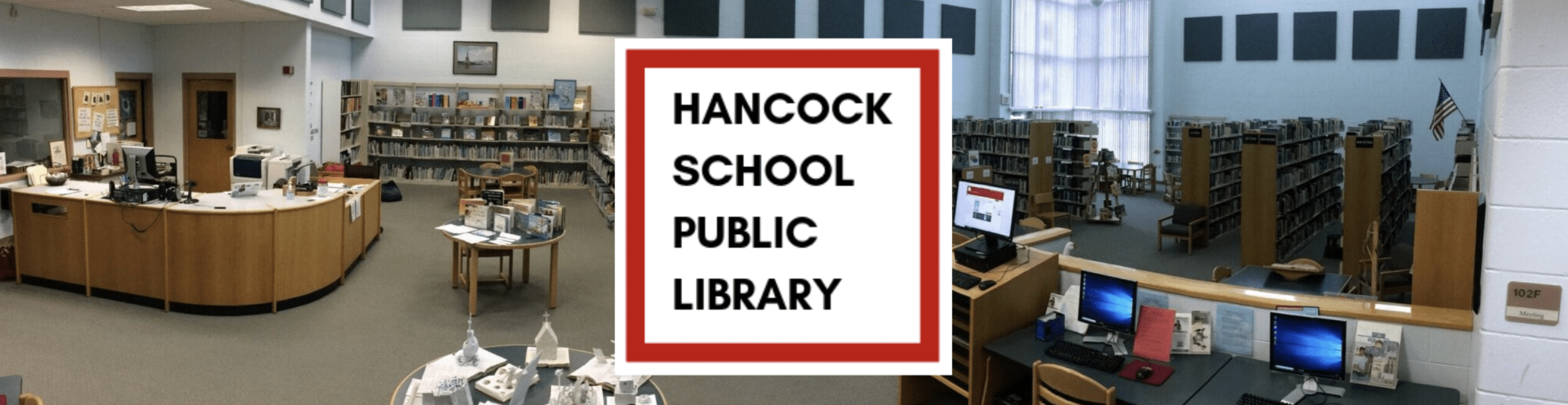 Interior of the Hancock School Public Library, showing bookshelves, computer stations and the library's service desk.