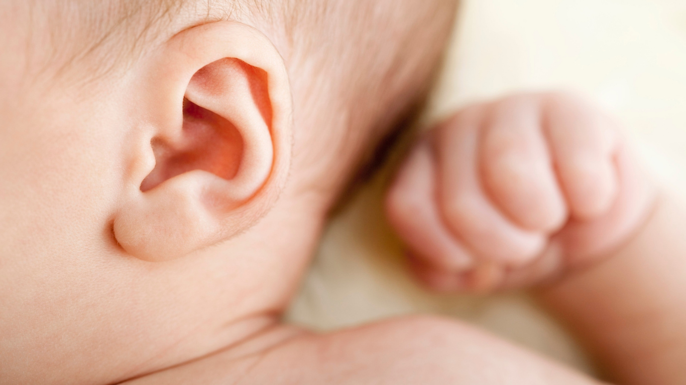 Close-up of a sleeping infant, focusing on the baby’s ear, cheek, and curled hand.