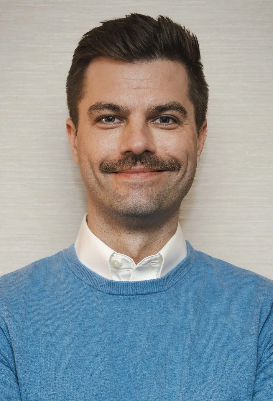 Joe Tollefson wearing a blue sweater over a white collared shirt.