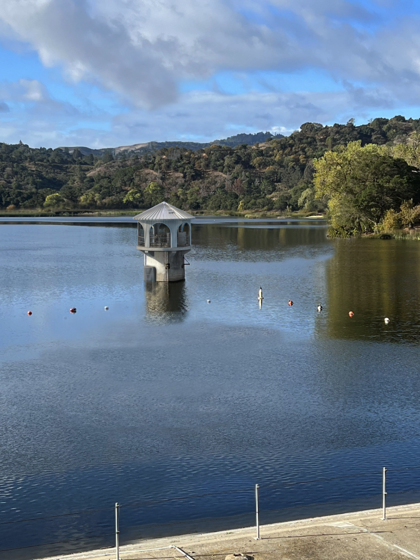 Lafayette Reservoir outlet tower standing in the water with wooded hills in the background.