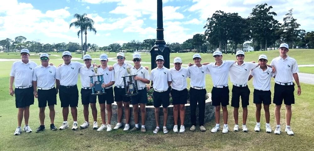 Lakewood Ranch High School boys golf team poses with trophies on a golf course after the Manatee County Championship.