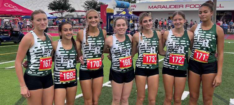 Seven Lakewood Ranch High School girls cross country runners pose with a championship trophy in their green and white uniforms.