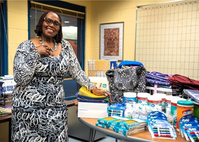 Parent Barbara Jones standing beside a table of school supplies.