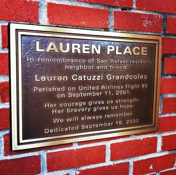 A bronze plaque on a brick wall reading 'Lauren Place,' dedicated to San Rafael resident Lauren Catuzzi Grandcolas, who died aboard United Airlines Flight 93 on Sept. 11, 2001.