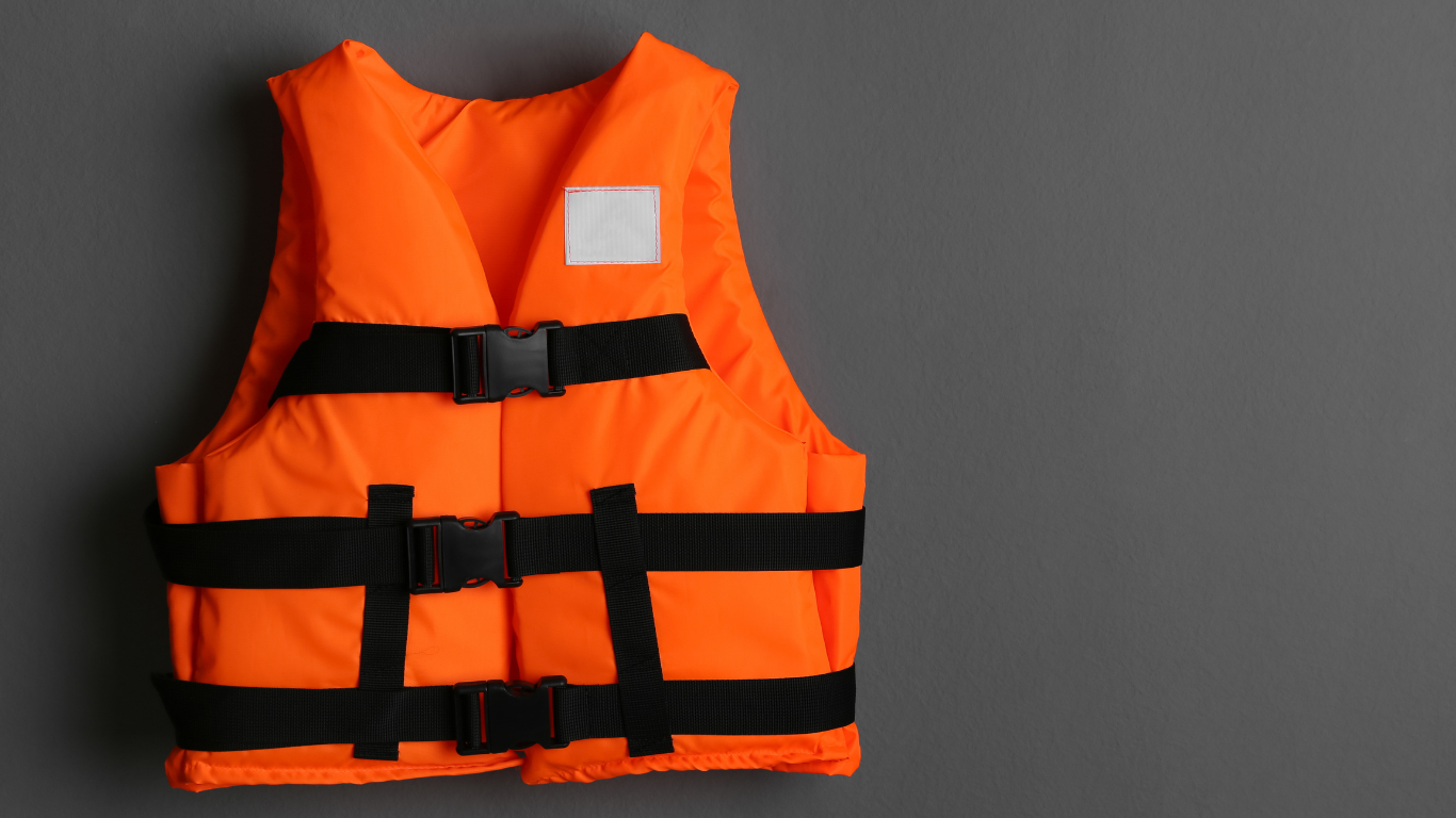 A bright orange life jacket with black safety straps and buckles displayed against a gray background.