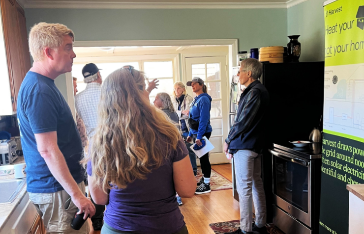 Attendees tour an electrified home's kitchen during a past Marin Green@Home Tour, viewing a heat-pump display banner and appliances.
