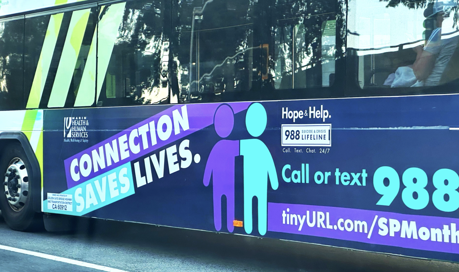A Golden Gate Transit bus displays a Marin County Health and Human Services ad reading 'Connection Saves Lives,' promoting the 988 Suicide and Crisis Lifeline.