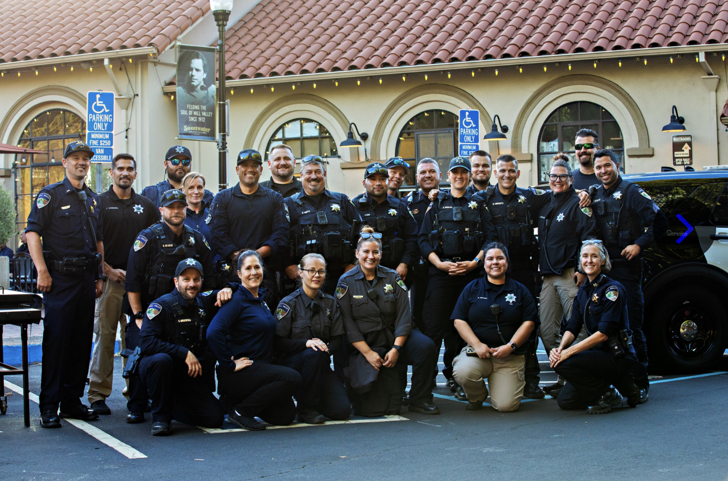 Members of the Mill Valley Police Department pose for a group photo with a patrol vehicle in downtown Mill Valley.