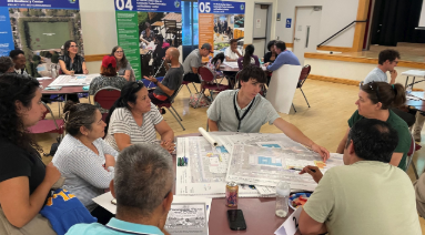 Community members sit around tables reviewing renovation plans and maps during a public workshop for the MLK Jr. Community Center project.