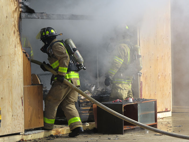 Firefighters enter a smoky, burnt room after a flashover fire demonstration