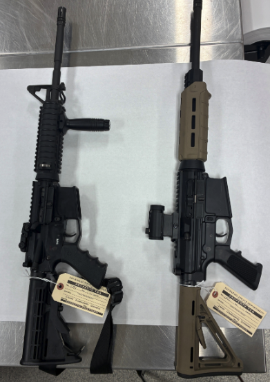 Two rifle-style firearms displayed on a table with evidence tags attached.