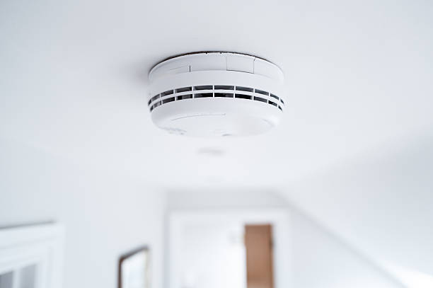 Shallow focus of a newly fitted mains operated smoke alarm detector seen in the upstairs landing of a modern house.