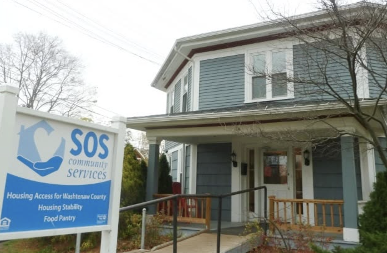 Exterior of SOS Community Services' building in Ypsilanti, with a sign reading "Housing Access for Washtenaw County, Housing Stability, Food Pantry."