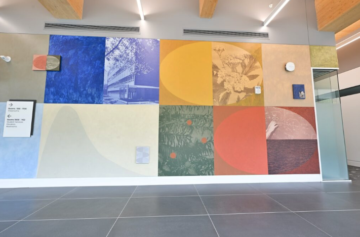 A section of the 100-foot "InterActions" mural inside the University of Michigan College of Pharmacy building, showing colorful geometric panels mixed with archival photographs and botanical imagery.