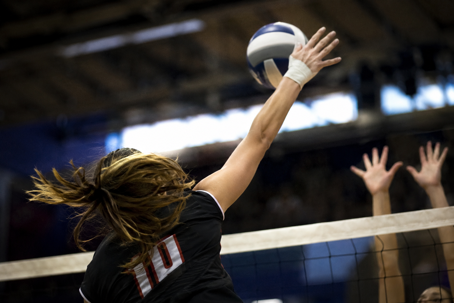 woman volleyball player hitting a ball over the net