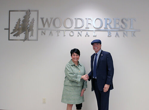 two people shaking hands in front of a bank sign