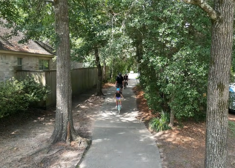 three people riding bikes on a path